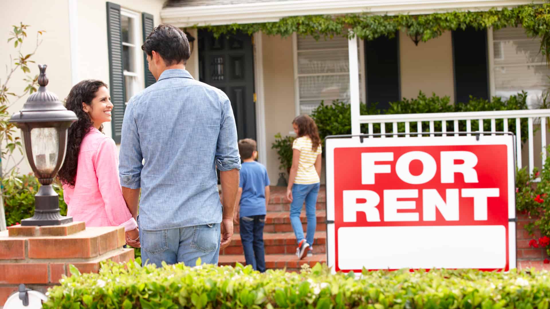 Let's talk A family standing in front of a house with a for rent sign.