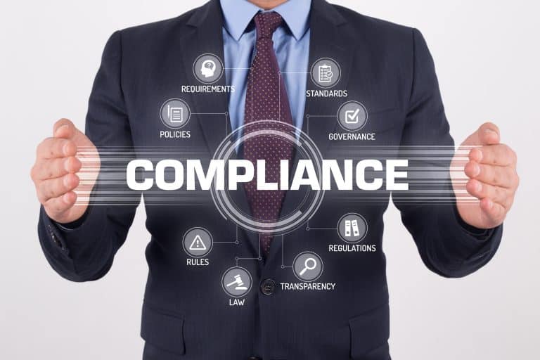 A man in a suit holding up the word compliance.