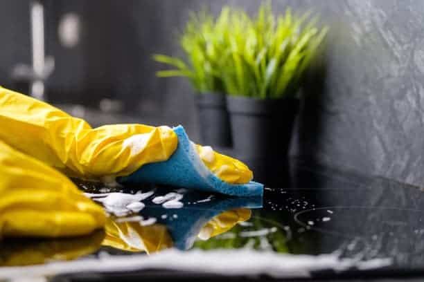 A person wearing yellow gloves cleaning a kitchen counter.