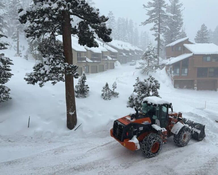 A bulldozer is driving down a snow covered road.